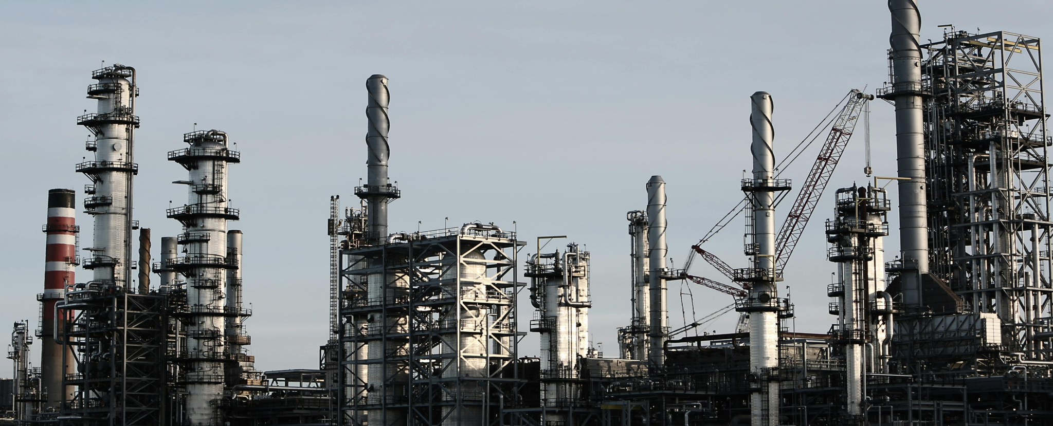 Petrochemical refinery with numerous towers, pipes, and smokestacks.